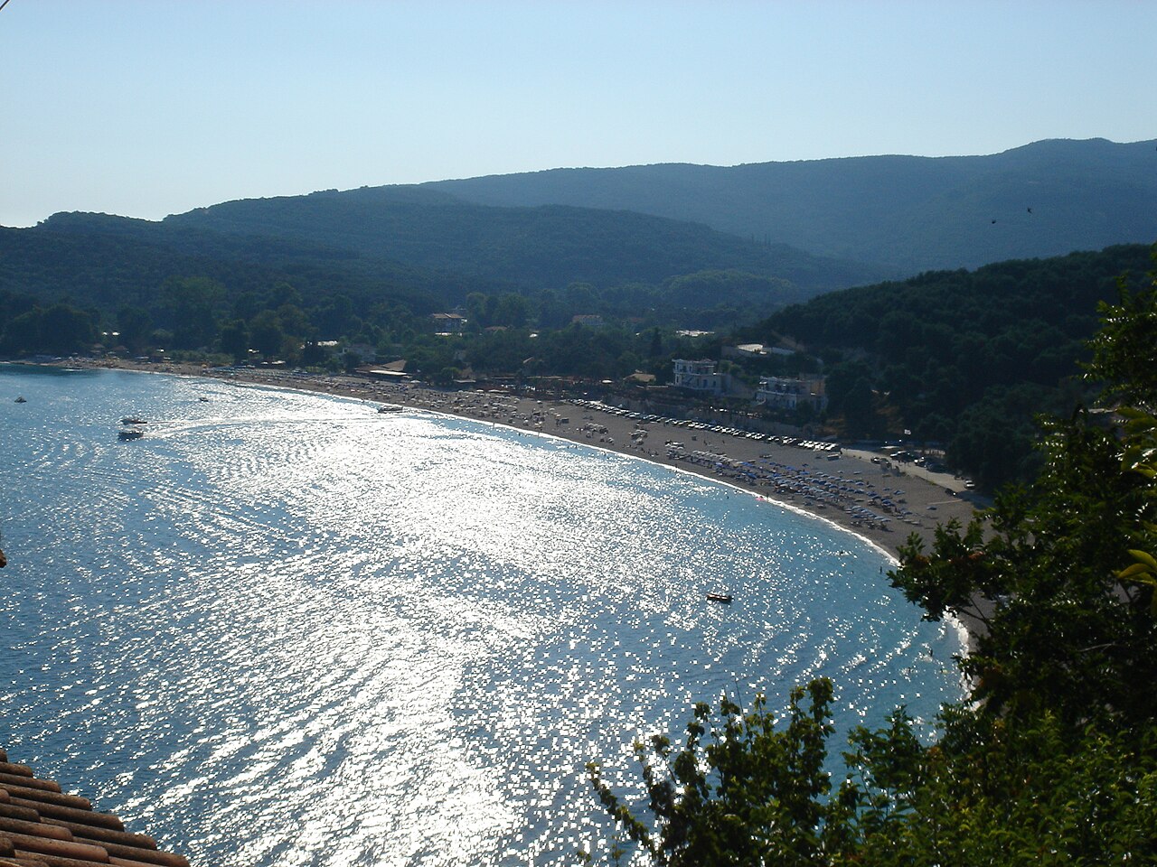 Valtos beach, a long curve of sand and bright water beneath wooded hills.